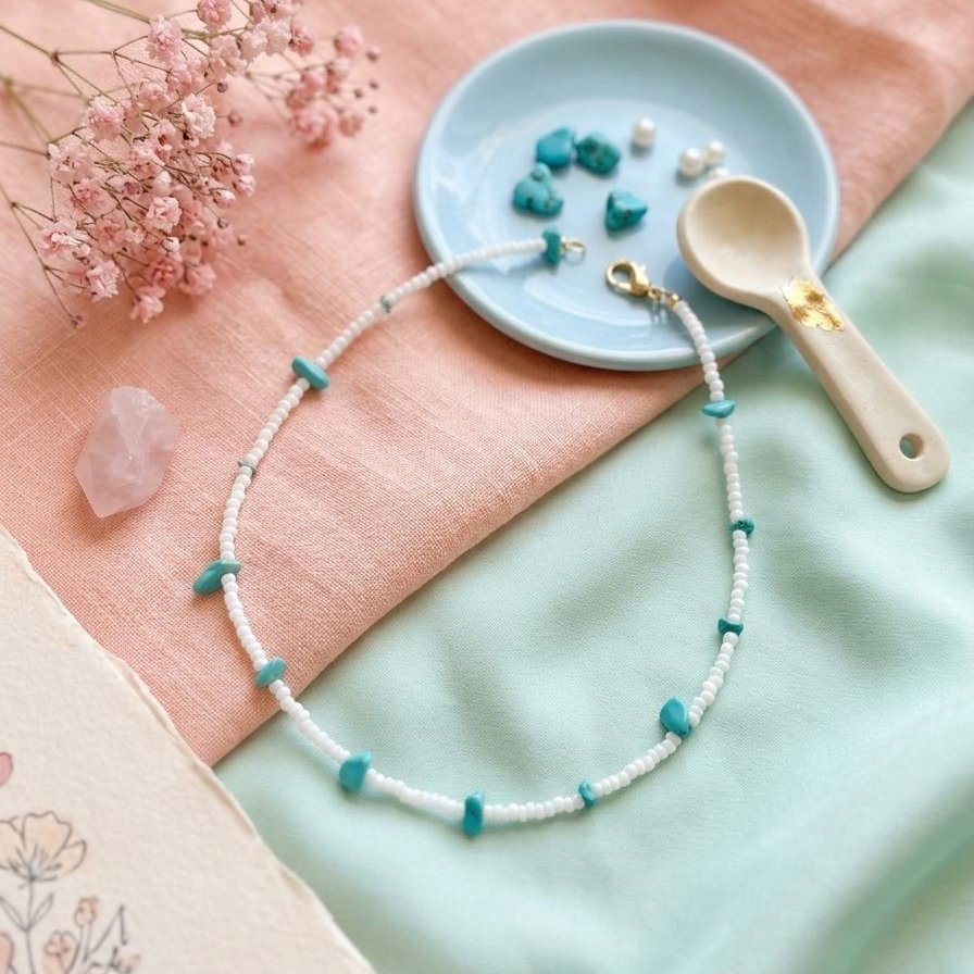 Collier de perles blanches ponctué d'éclats de turquoise